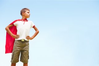 Boy dressed as a super hero in a red cape.