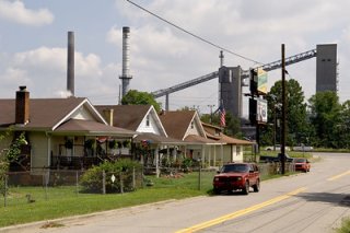 Neighborhood showing homes and vehicles on the street with an industrial site in the background