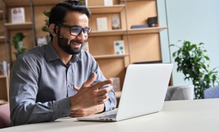 Image of a gentleman sitting on a virtual conference and being engaged in conversations. 