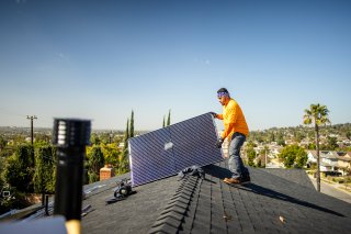 Man carries solar panel on roof