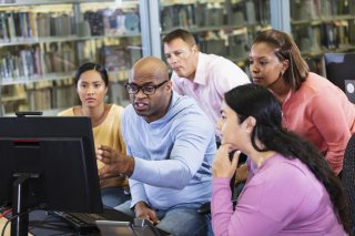 Group of adults look at a computer together