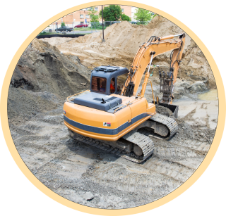 An excavator in an empty lot scooping dirt.