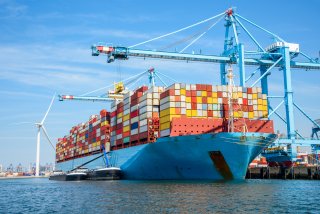 Cargo ship in the water with numerous containers on it.