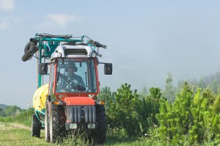 man in tractor applying pesticides to farmland