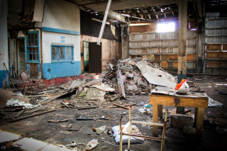 A pile of debris sits in the middle of a dilapidated brick industrial building.