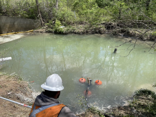 An environmental contractor observes cleanup tools in action in the impacted waterway.