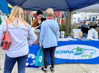 two women standing at an OCRRA booth at a fair