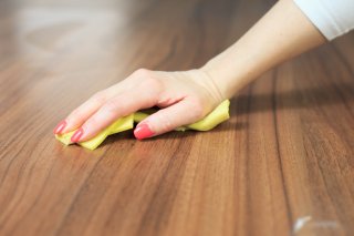 a hand with a dust cloth dusting a table top