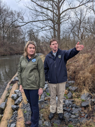 Two people pointing at something while standing near a waterway