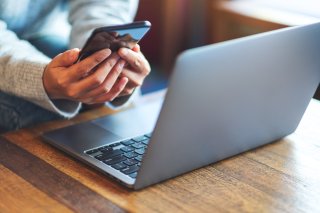 Person in front of a computer on their phone