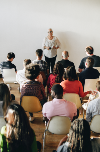 Group of people listen to a presenter talking at a community meeting