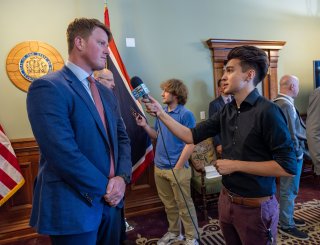Cyrus Western being interviewed at an event by a reporter holding a microphone