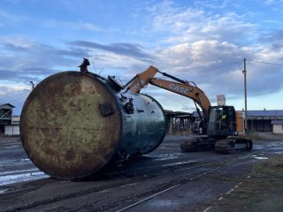 Heavy equipment moving a large industrial tank.