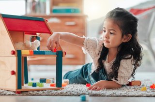 A young girl plays with toy blocks in a children's bedroom.