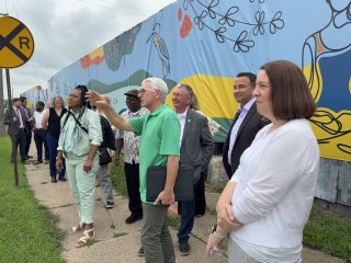 A group of people line up along a mural on a site tour of brownfield sites in Dubuque, Iowa.