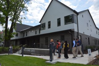 A small group of people walk in front of the Heroes Home Gate building at its grand opening.