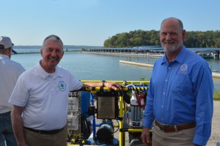 Two men pose in front of an emergency water response tool called the Water on Wheels cart.