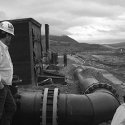 two humans standing in the Butte Mining flood operable unit with a large pipe in the background.