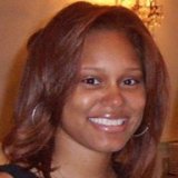 A dark-skinned woman with shoulder-length dark red hair, smiling.