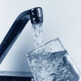 Glass being filled with water from kitchen tap