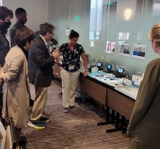 EPA scientist talking while standing in front of microscopes and agar plates surrounded by 5 people listening