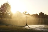 A sprinkler is watering a golf course 