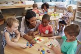 Adult sits with kids at child care